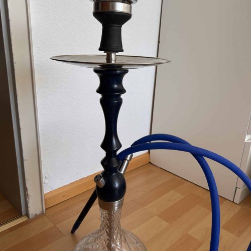 Shisha mit Glasbowl, Schlauch und Kopf, auf Holzboden.