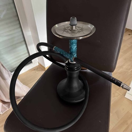 Shisha mit Glasbowl, Schlauch und Kopf auf Stuhl.