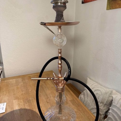 Shisha mit Glasbowl, Metall- und Glasbestandteilen, auf Holztisch.