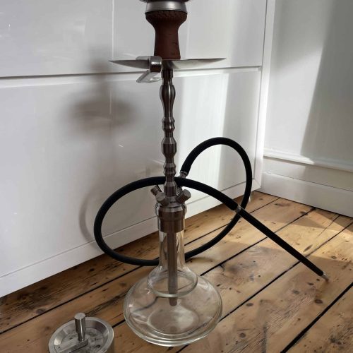 Alte Shisha mit Glasbase, Metallkopf und Schlauch, bereit zum Rauchen.