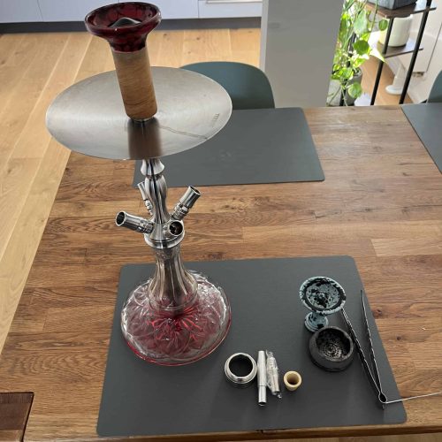 Shisha mit Glasbowl, Schlauch und Tabak auf Tisch, bereit zum Rauchen. Perfektes Setup für Shisha-Li.