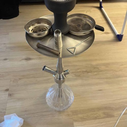 Shisha mit Tabak, Kohle und Zubehör auf einem Tisch.