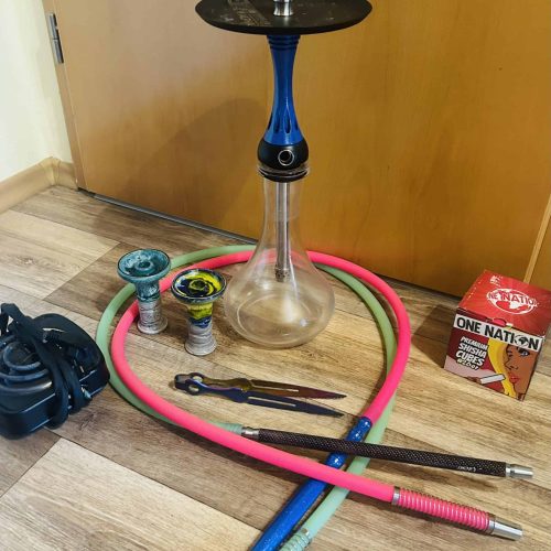 Shisha mit Glasbowl, Schläuchen und Zubehör im Raum.