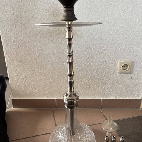 Shisha-Kopf mit Glasbowl und Zubehör auf Boden.