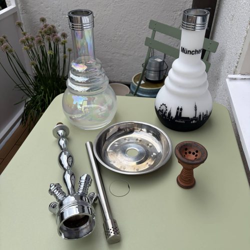 Verschiedene Shisha-Teile und Glasbowl auf Tisch.