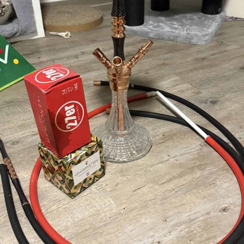Wasserpfeife mit Schlauch, Tabak und Zubehör auf Holztisch.