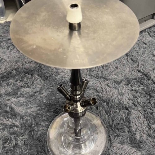 Shisha-Tabak mit Glasbowl und Metallaufsatz auf Teppichboden.