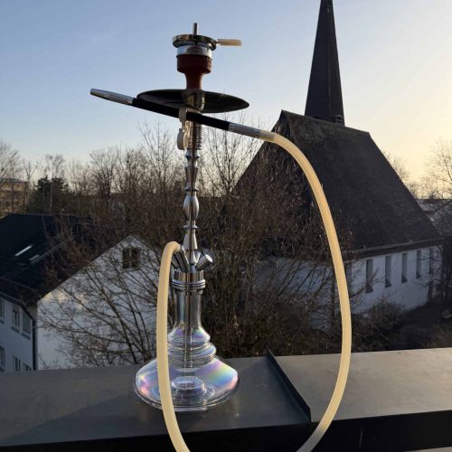 Shisha auf Balkon mit Blick auf Kirche und Bäume im Hintergrund.
