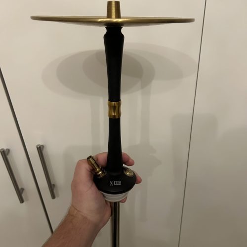 Shisha-Kopf mit Ablage, handgehalten, gegen weiße Schranktür.