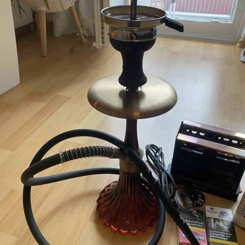 Shisha mit Glasbowl, Schlauch und Kohleofen auf Holztisch.
