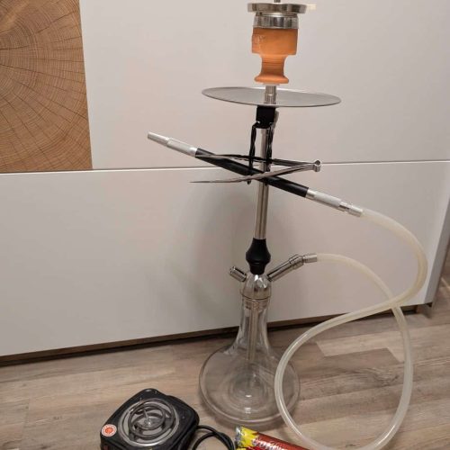 Shisha mit Glasbowl, Schlauch und Heizgerät auf Boden.