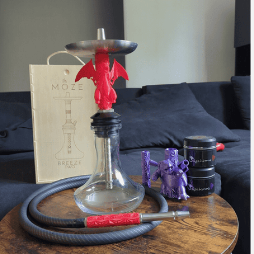 Shisha mit rotem Drachen-Design und Zubehör auf Tisch.