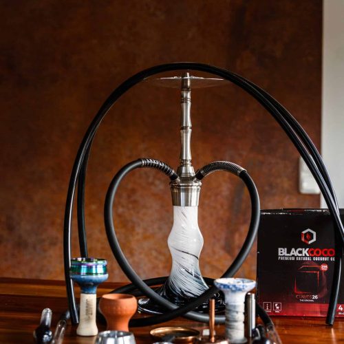 Moderne Shisha mit Glasbowl und Zubehör auf Holztablett.
