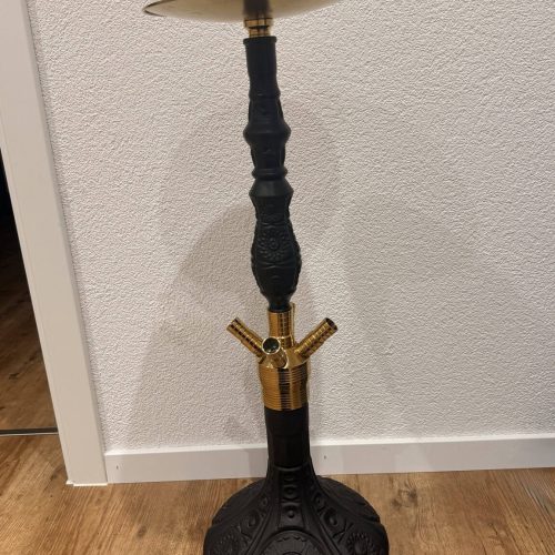 Schwarzer Shisha-Kopf mit goldener Glasbowl auf Boden.