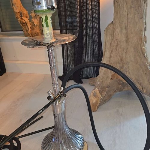 Wasserpfeife mit Rauchsäule, Dekoration und Zubehör im Raum.