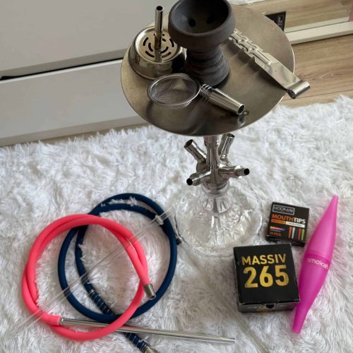 Raucherset mit Shisha, Schläuchen, Tabak und Zubehör auf weichem Teppich.