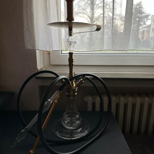 Moderne Shisha mit Glasbowl und Schlauch auf Tisch.