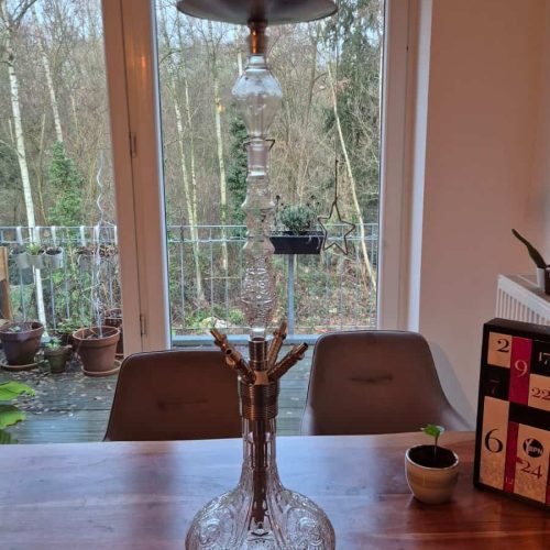 Rauch-Hookah mit Glasbasis, Holzaufsatz und Deko im Wohnzimmer.