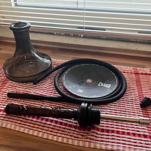 Shisha-Set mit Rauchsäule, Schlauch und Düse auf Tisch.
