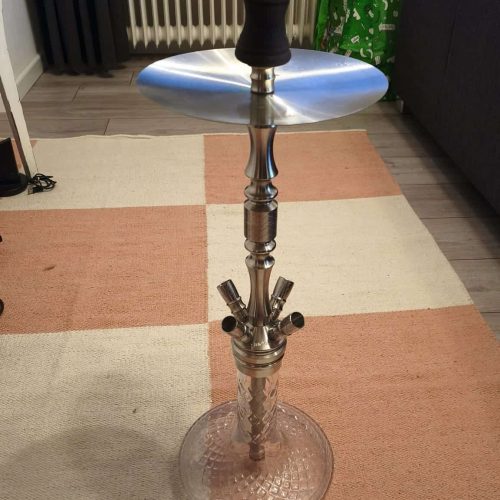 Shisha-Kopf mit Glasbowl und Metallstange, auf Teppichboden.
