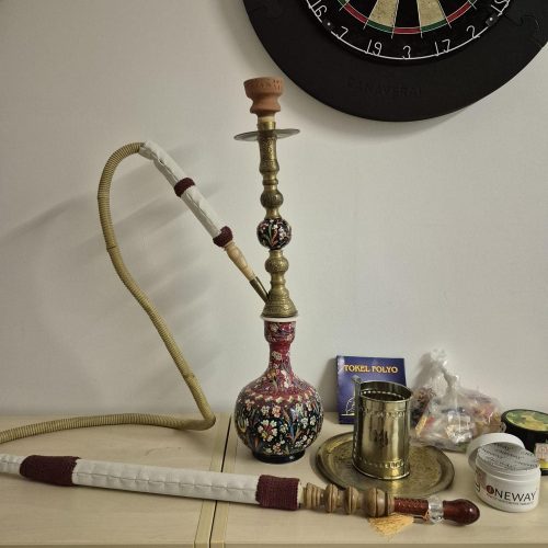 Shisha mit bunter Glasbowl und Dartscheibe im Hintergrund.
