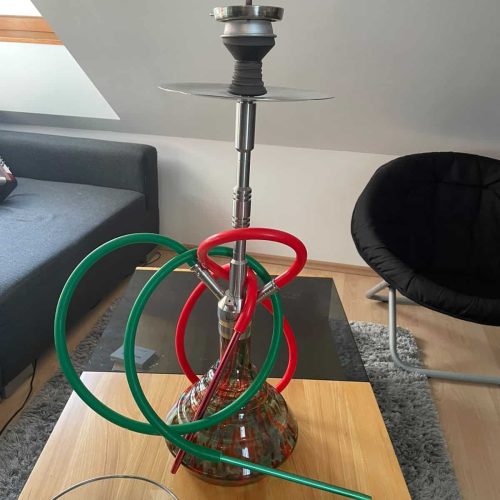 Shisha mit Glasbowl, Schlauch und Zubehör auf Tisch.