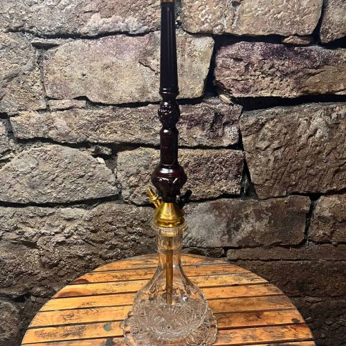 Rauch-Hookah mit Glasbasis und Metallständer auf Holztisch.