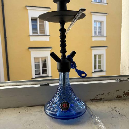 Shisha mit blauer Glasbasis und Wasserpfeife auf Fensterbank.