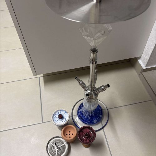 Shisha mit verschiedenen Ersatzteilen und Zubehör auf Fliesenboden.