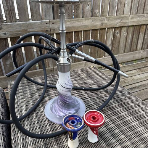 Shisha mit Glasbowl, Schlauch und Kopf auf Tisch.