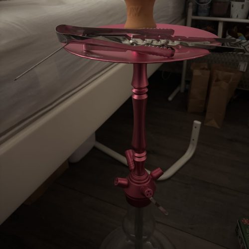 Rauch-Hookah auf einem Glastisch mit Zubehör, in einem Raum mit Bett und Schränken.