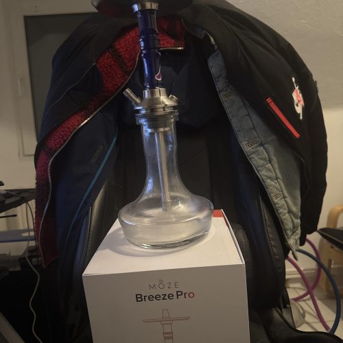 Schwarze Shisha mit Glasbowl, Metallaufsatz und Schlauch, auf einem weißen Präsentationsständer.