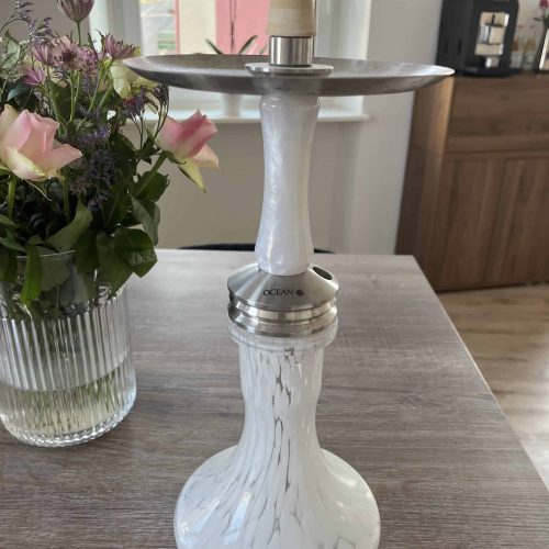 Weiße Shisha mit Marmor-Optik und Metallaufsatz auf Tisch.