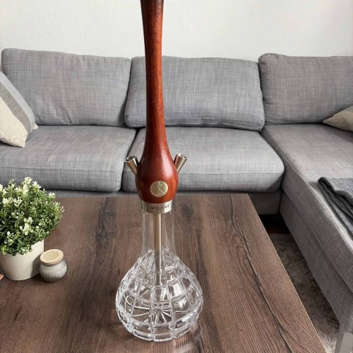 Shisha-Kopf mit Holzstück und Glasbowl auf Tisch.