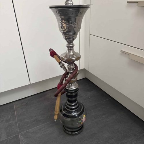 Rauch-Hookah mit silbernem Kopf und Schlauch auf Fliesenboden.