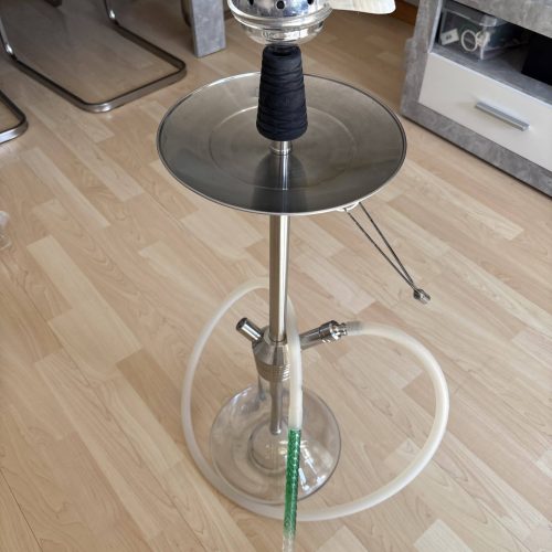 Shisha mit Glasbowl, Schlauch und Tabakkopf in Wohnzimmer.