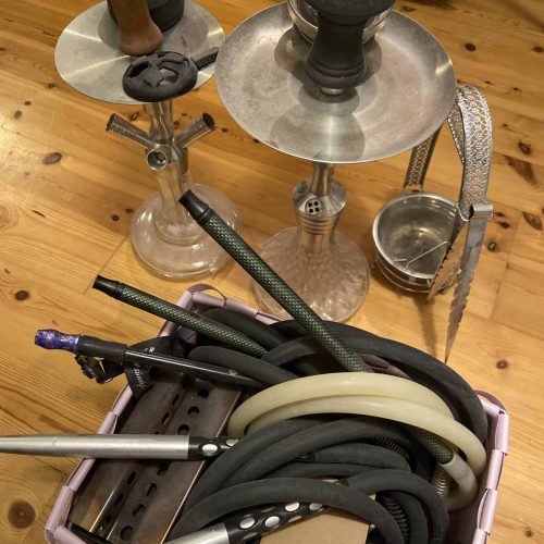 Verschiedene Shisha-Teile und Glasbowl auf Holzboden.