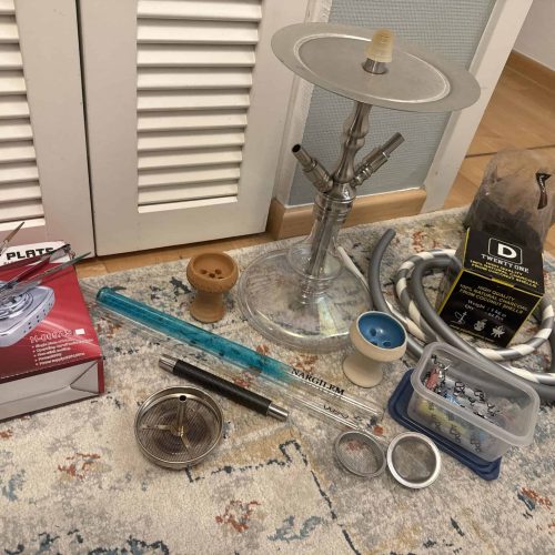 Verschiedene Shisha Teile und Glasbowl auf Teppichboden.