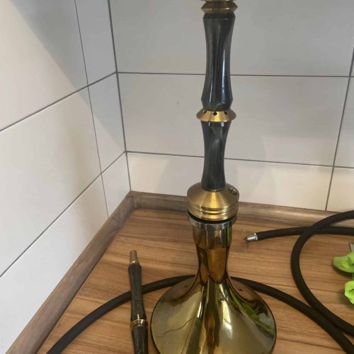 Dekorative Shisha mit schwarzem und goldenem Design, auf Holzoberfläche in Küche oder Lounge.