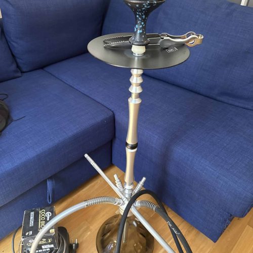 Rauchersäule mit Shisha, Wasserpfeife und Zubehör auf Couch.