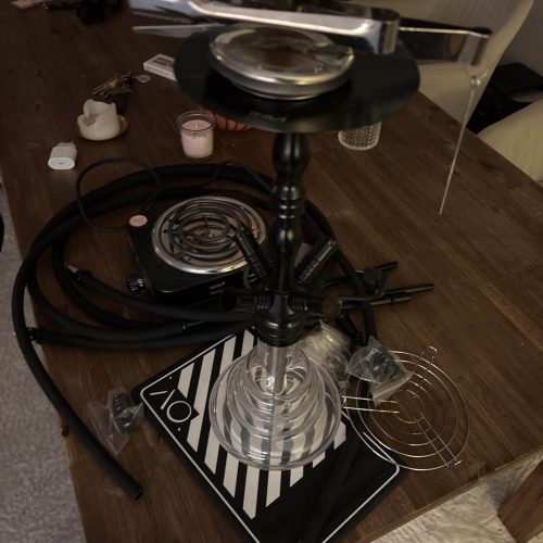 Rauchsäule mit verschiedenen Shisha-Teilen auf einem Tisch, bereit für den Gebrauch.