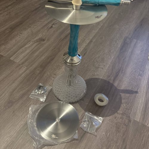 Rauchsäule mit Shisha, Zubehör und Verpackung auf Holzboden, bereit für den Gebrauch.
