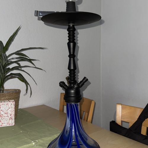 Rauchpfeife mit blauer Glasbasis auf Esstisch.