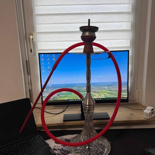 Shisha mit roter Schlauch und Glasbowl vor Fenster.