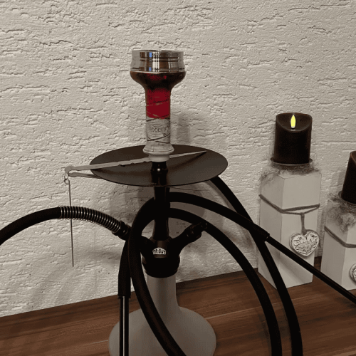 Dampfer mit Wasserpfeife, Tabak und Zubehör auf Holzoberfläche.