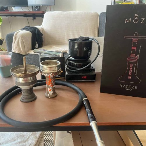 Shisha-Zubehör mit Kohle, Tabak und Zubehör auf Tisch.