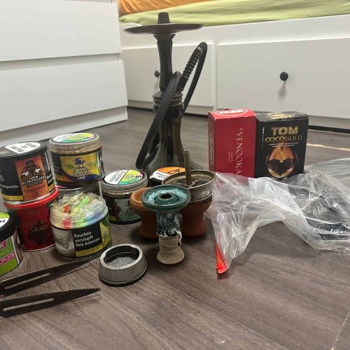Verschiedene Shisha-Teile, Tabak und Zubehör auf dem Boden.