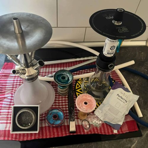 Shisha mit Kohle, Tabak und Zubehör auf Tisch.