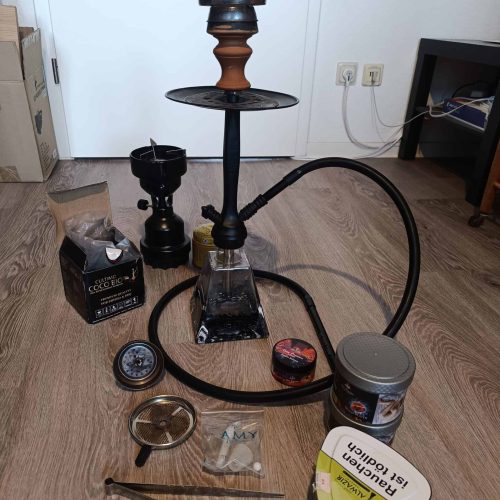 Shisha mit Glasbowl, Schlauch und Tabak, auf Holzboden.