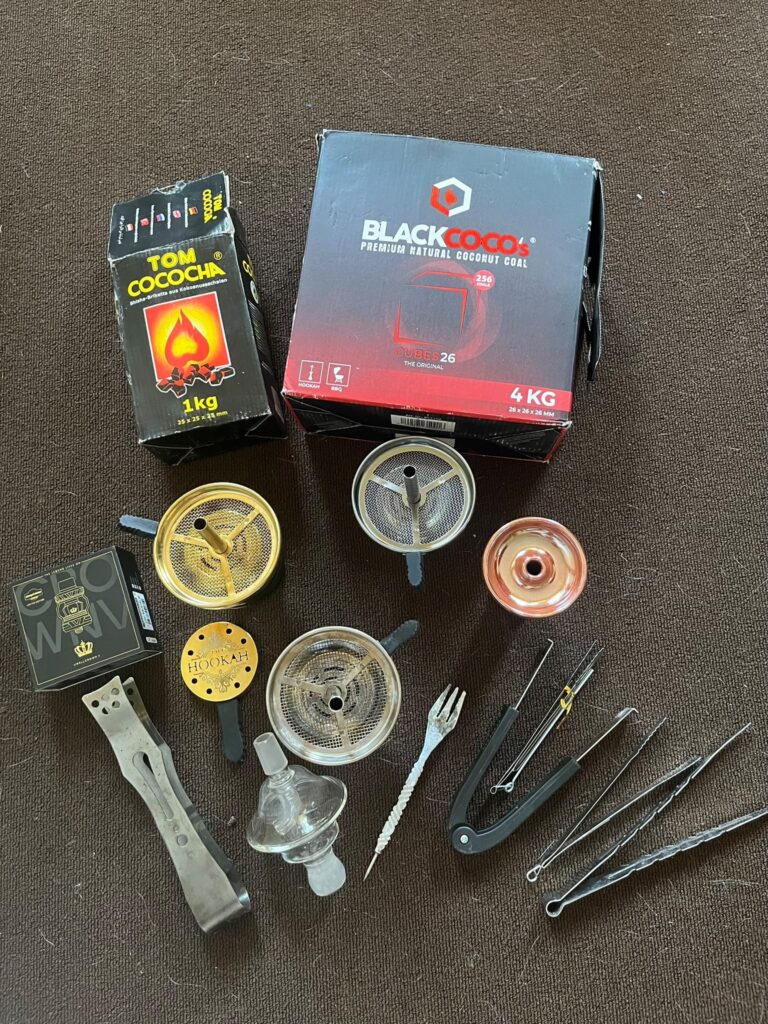 Verschiedene Shisha Zubehörteile, Kohle, Zangen und Glasbowl im Set.